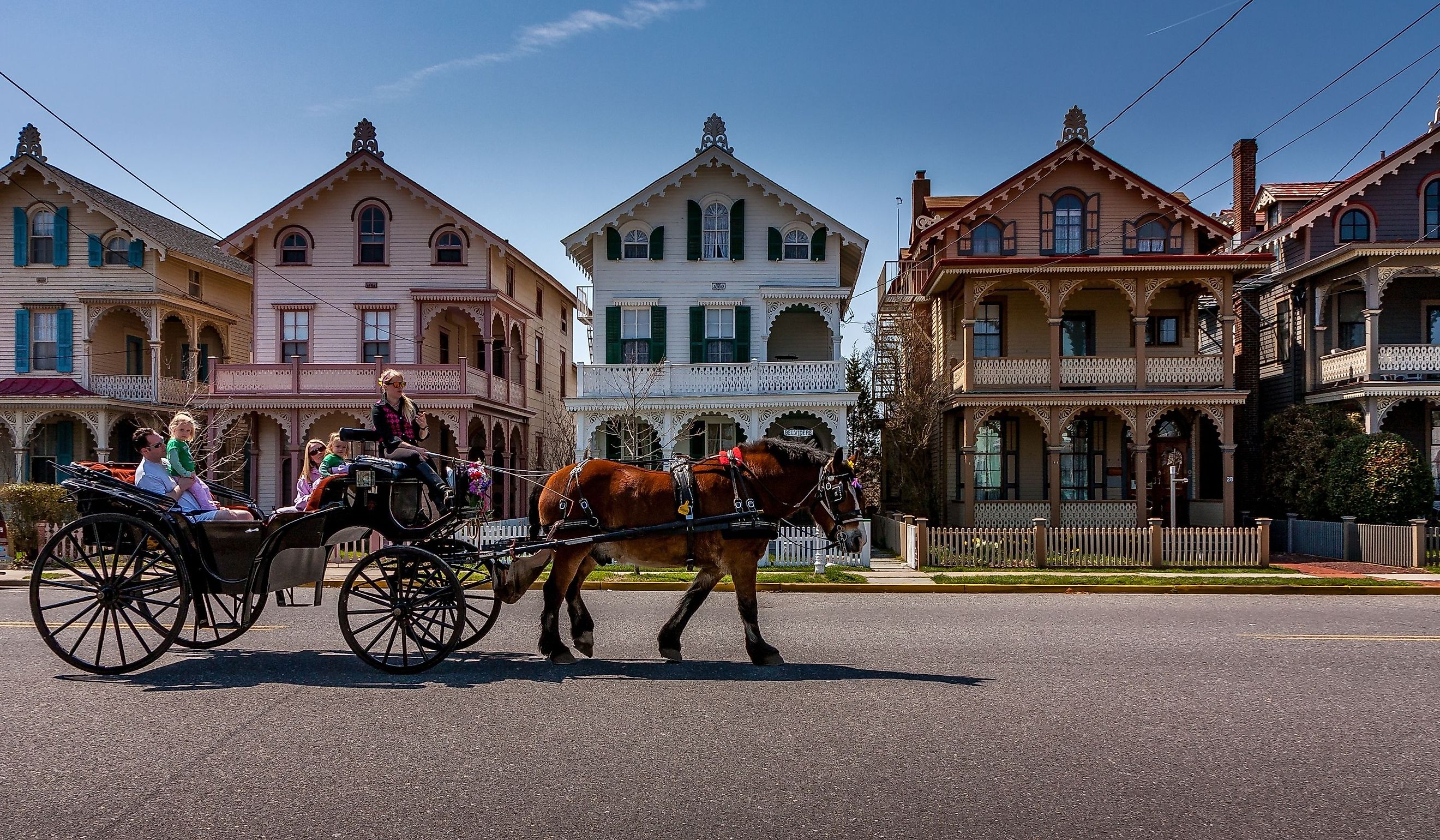 A carriage carries tourists past a row of Victorian "gingerbread" houses typical of Cape May, NJ. Editorial credit: Steve Rosenbach / Shutterstock.com