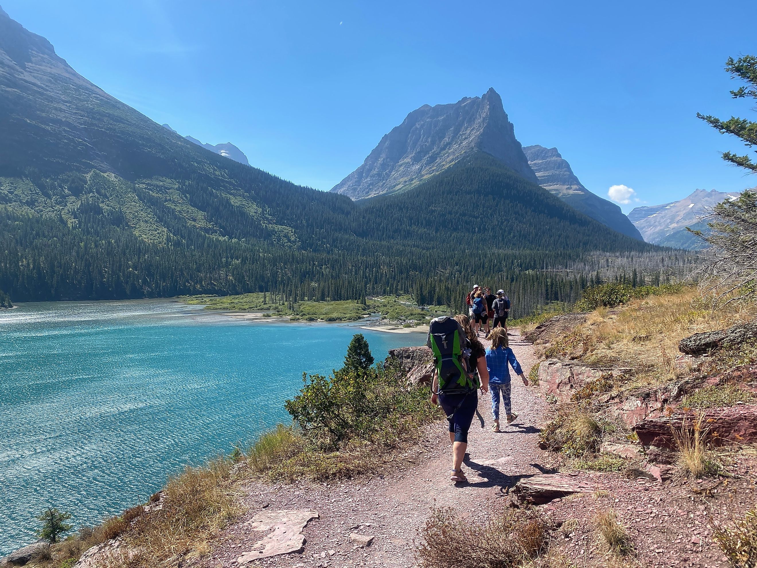 Hikers on the Three Falls Trail with Saint Mary Lake and mountains in the background, Glacier National Park, Montana. Editorial credit: christopher babcock / Shutterstock.com