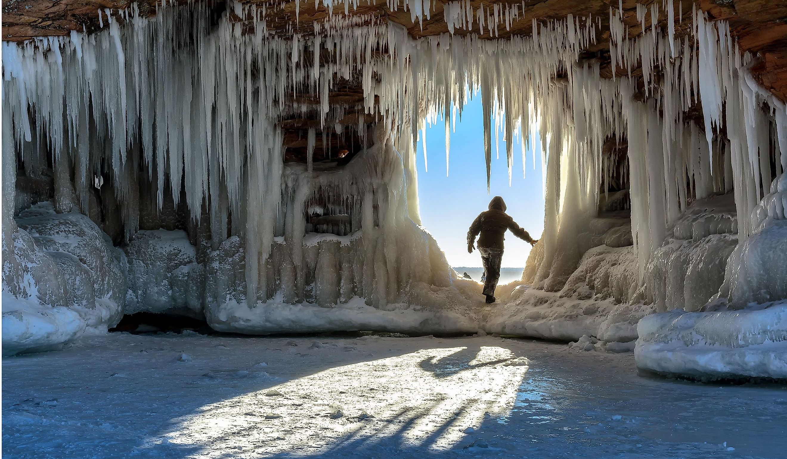 A person steps through an icicle-laden hole in the sandstone formations on Wisconsin's Apostle Islands National Lakeshore near Meyer's Beach, Lake Superior.