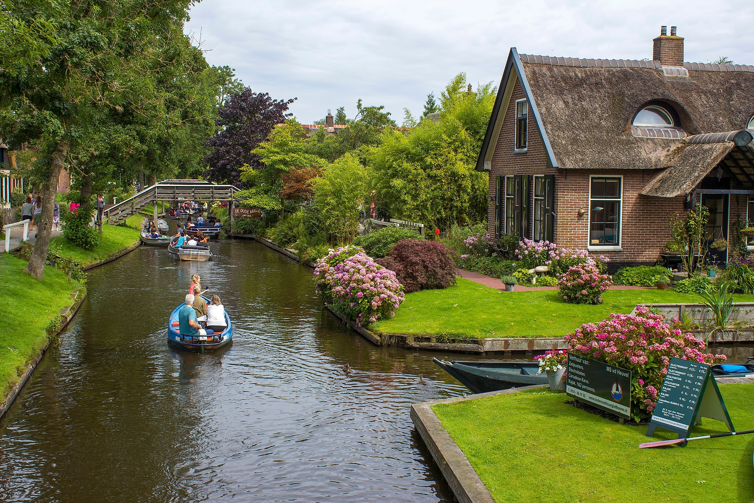 Visitors on a sightseeing boat trip through a canal in Giethoorn, Netherlands. Editorial credit: Mira Drozdowski / Shutterstock.com