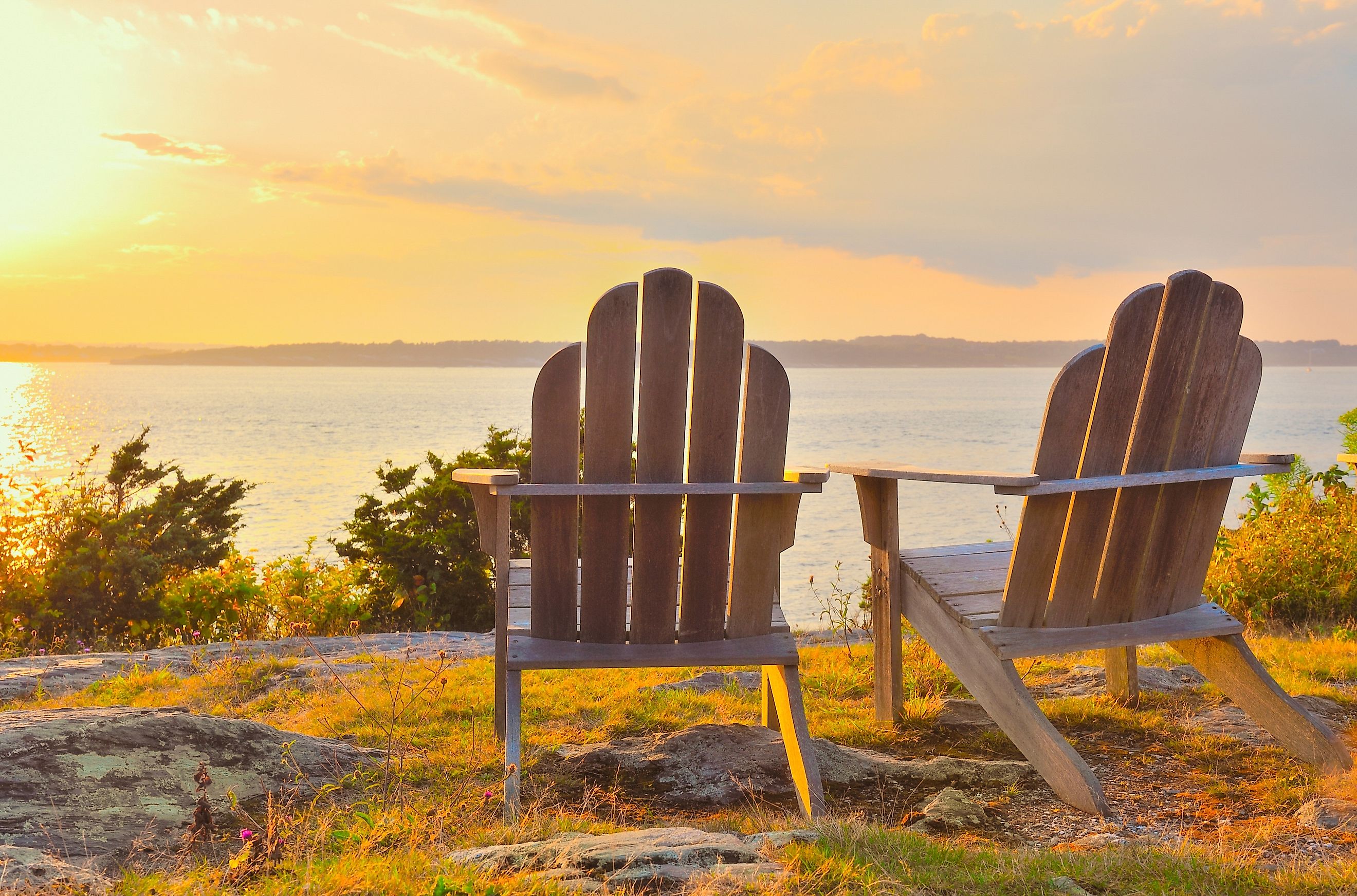 Adirondack chairs on cliff overlooking the water Narragansett Bay at sunset, late summer, early fall, golden hour Newport, Rhode Island