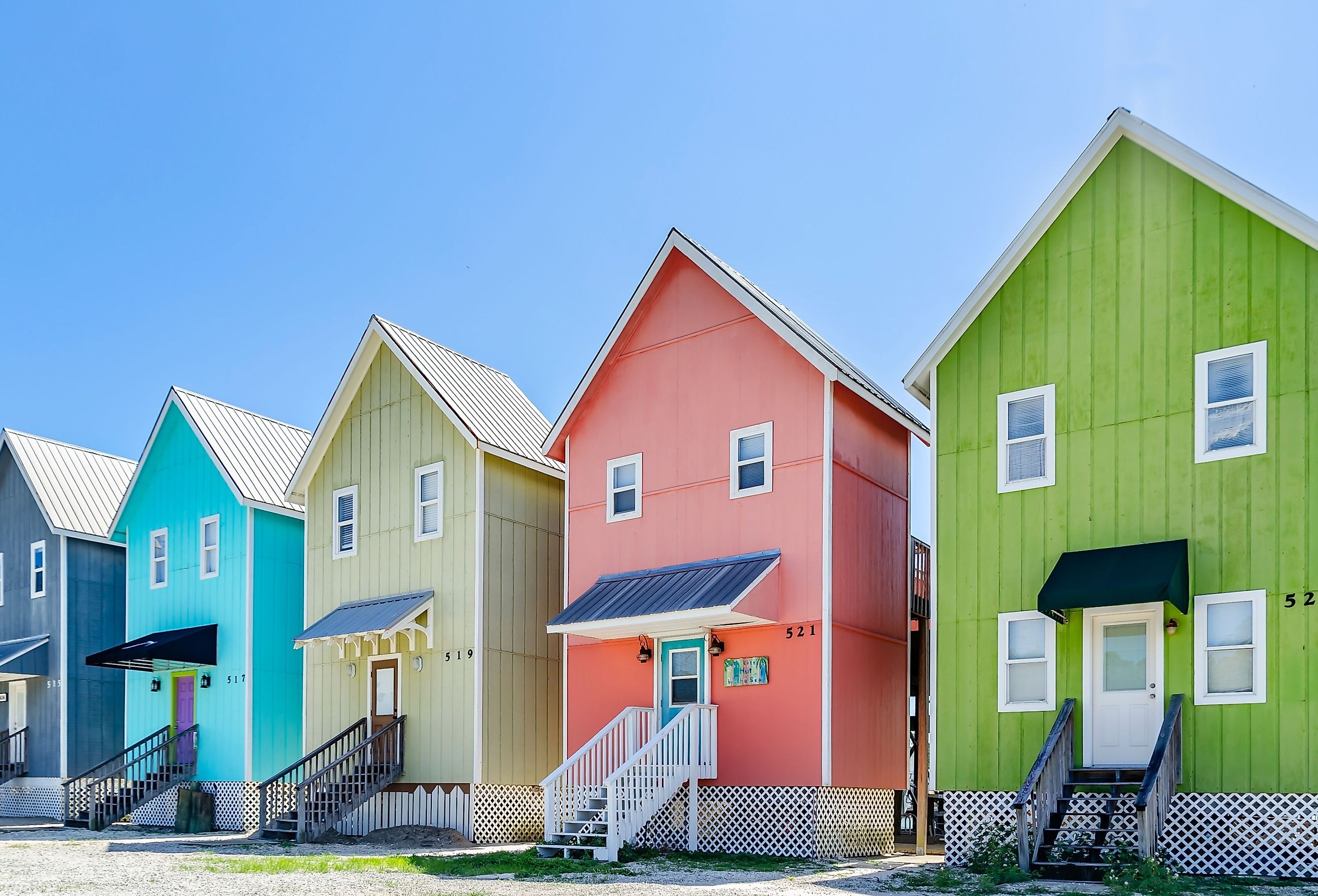 A row of colorful beach houses known as “The Birdhouses” overlook Bayou Aloe, in Dauphin Island, Alabama. Image credit  Carmen K. Sisson via Shutterstock.