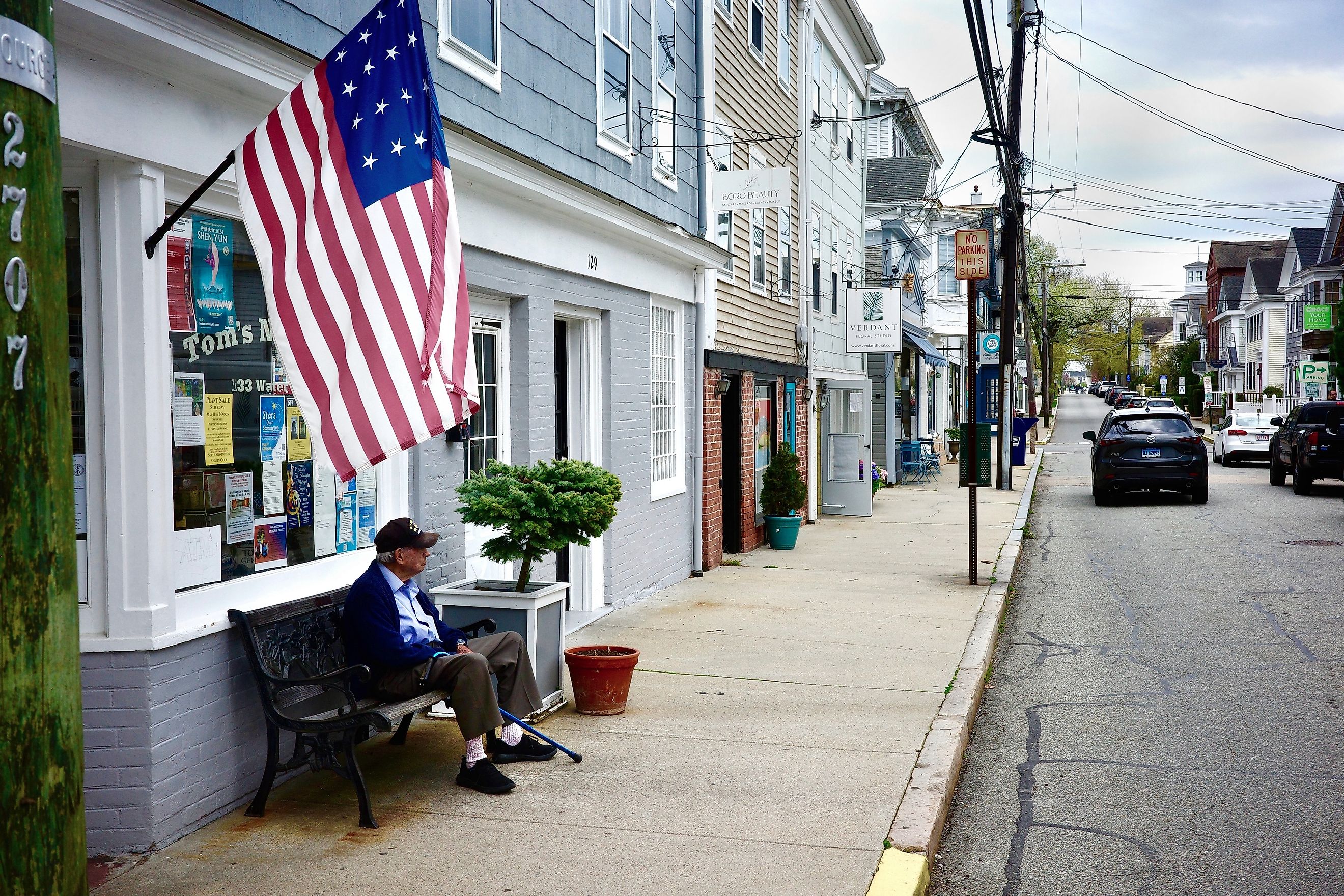 An elderly man seated under an old American flag on Main Street in Stonington, Connecticut. Editorial credit: Joe Tabacca / Shutterstock.com